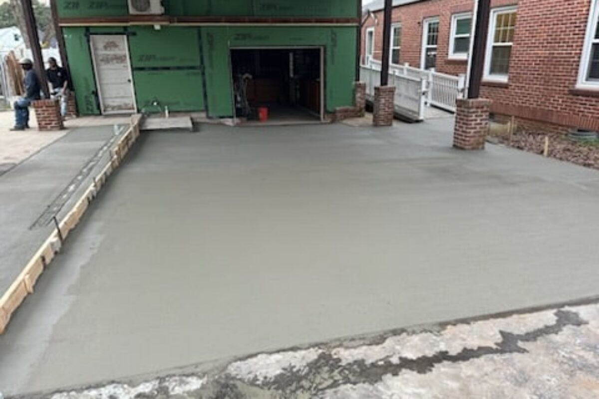 photo of freshly poured concrete around a brick building